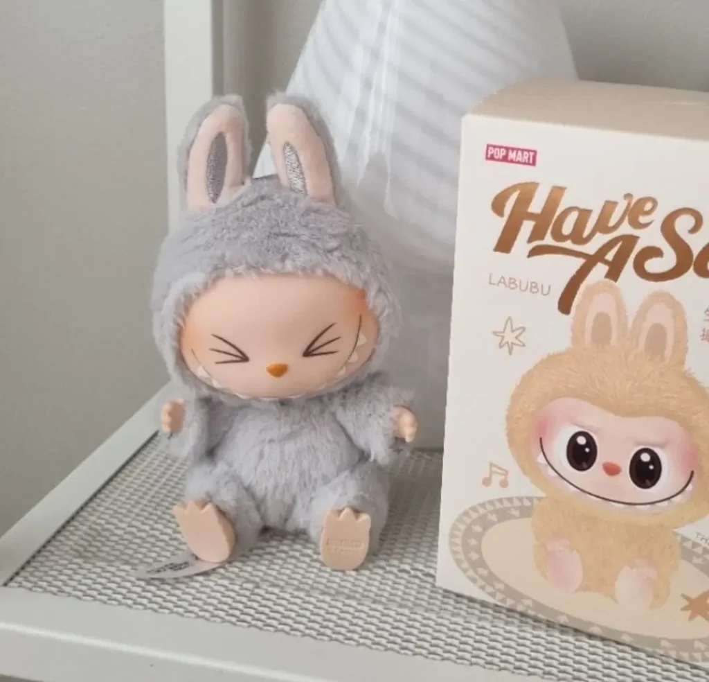 Hehe Labubu posed on a work desk with a book prop and neutral background